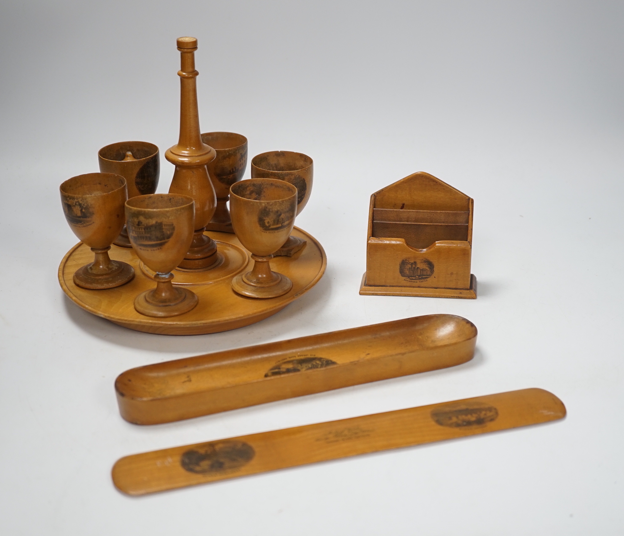 A collection of mixed Mauchline wares, including six egg cups on stand, a house money box, various boxes, letter openers and a Scottish song book, 14cm high (16)